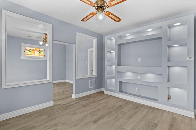 empty room with built in features, ceiling fan, and light wood-type flooring