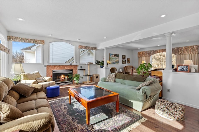 living room with ornate columns, wood-type flooring, plenty of natural light, and a high end fireplace