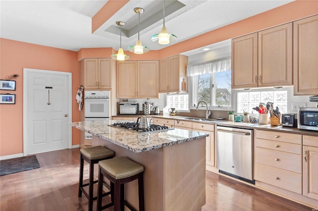 kitchen featuring stainless steel appliances, a kitchen island, and light brown cabinets