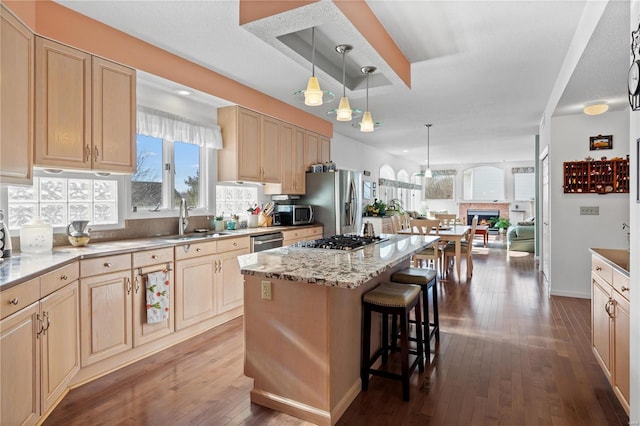 kitchen with a center island, sink, light brown cabinets, and a kitchen breakfast bar