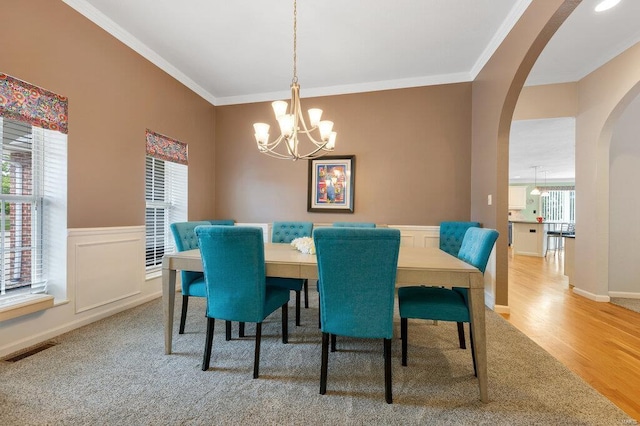 dining area featuring an inviting chandelier, ornamental molding, and hardwood / wood-style flooring