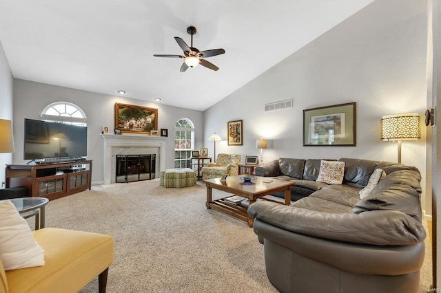 living room featuring ceiling fan, high vaulted ceiling, a premium fireplace, and carpet floors