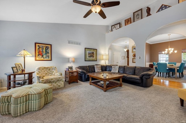 carpeted living room with crown molding, a towering ceiling, and ceiling fan with notable chandelier