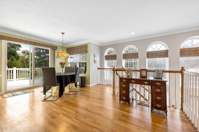 dining space with crown molding and light wood-type flooring