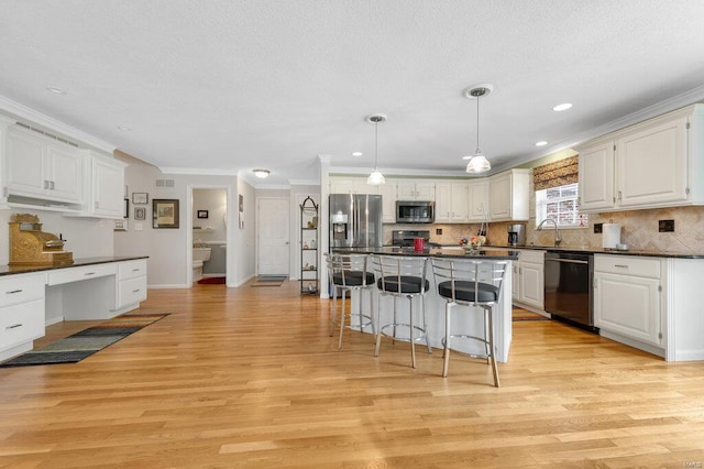 kitchen with crown molding, appliances with stainless steel finishes, white cabinets, a kitchen island, and light wood-type flooring