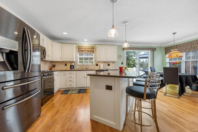 kitchen with white cabinetry, stainless steel appliances, and hanging light fixtures