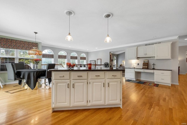 kitchen featuring white cabinetry, ornamental molding, a center island, and hanging light fixtures