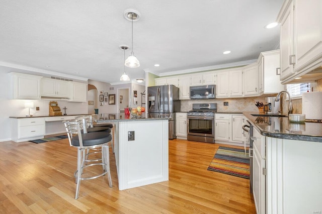 kitchen featuring sink, white cabinetry, a center island, appliances with stainless steel finishes, and light hardwood / wood-style floors