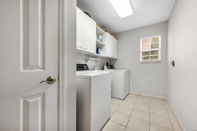 laundry room featuring washer and clothes dryer, cabinets, and light tile patterned flooring