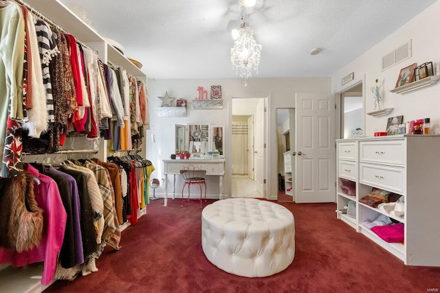 spacious closet featuring a notable chandelier and dark colored carpet