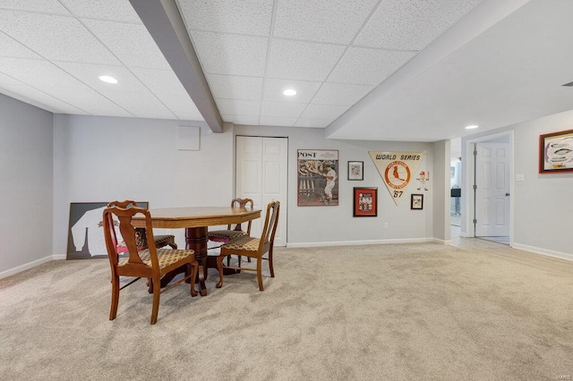 dining area with light carpet and a paneled ceiling