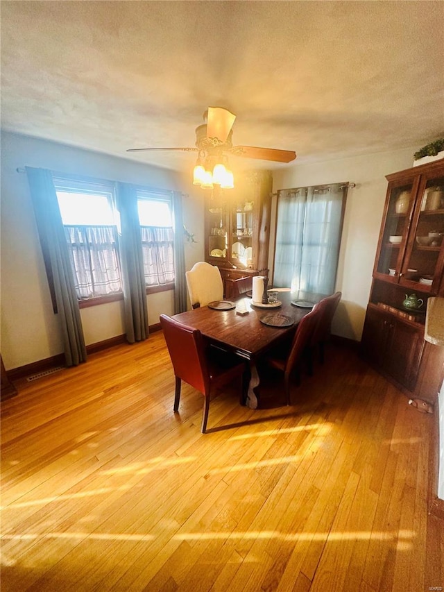 dining room with ceiling fan, light hardwood / wood-style floors, and a textured ceiling