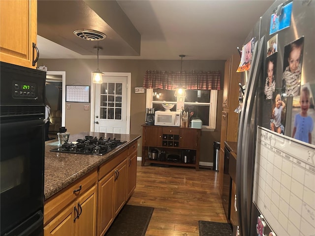 kitchen featuring pendant lighting, dark stone counters, dark hardwood / wood-style flooring, and black appliances