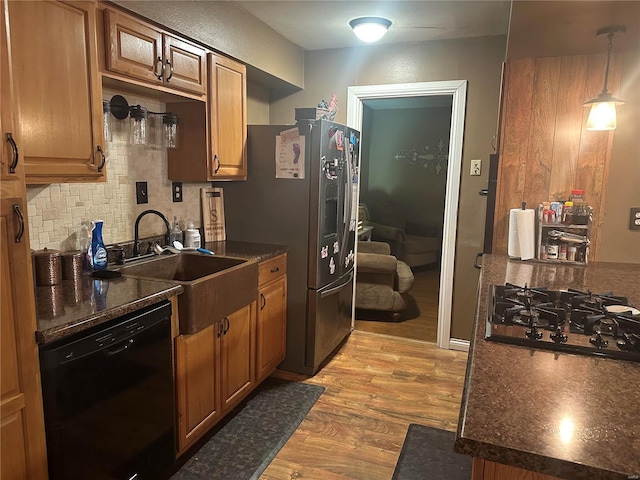 kitchen featuring sink, hanging light fixtures, tasteful backsplash, black appliances, and light wood-type flooring