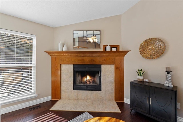 living room with dark hardwood / wood-style flooring, a fireplace, a textured ceiling, and vaulted ceiling