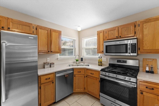 kitchen with light tile patterned flooring, appliances with stainless steel finishes, sink, and a textured ceiling