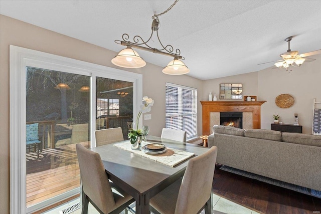 dining space with lofted ceiling, ceiling fan, hardwood / wood-style flooring, and a textured ceiling