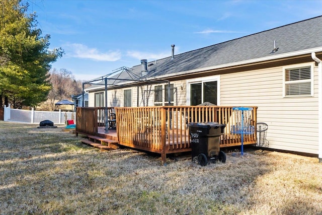 rear view of property featuring a wooden deck and a lawn