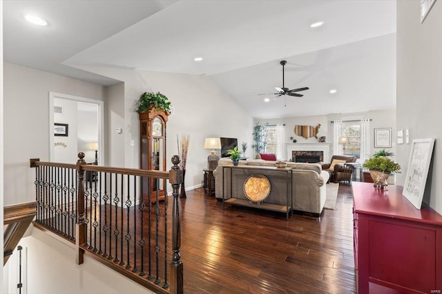 living room with dark wood-type flooring, ceiling fan, and vaulted ceiling