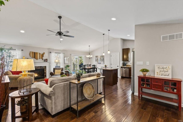 living room featuring a premium fireplace, vaulted ceiling, ceiling fan with notable chandelier, and dark hardwood / wood-style flooring