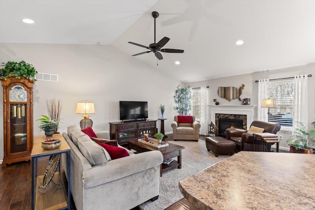 living room featuring a premium fireplace, lofted ceiling, a healthy amount of sunlight, and ceiling fan