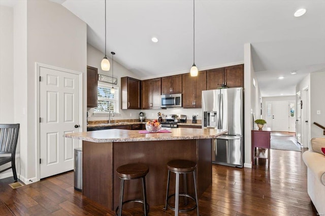 kitchen featuring a kitchen island, appliances with stainless steel finishes, lofted ceiling, sink, and hanging light fixtures