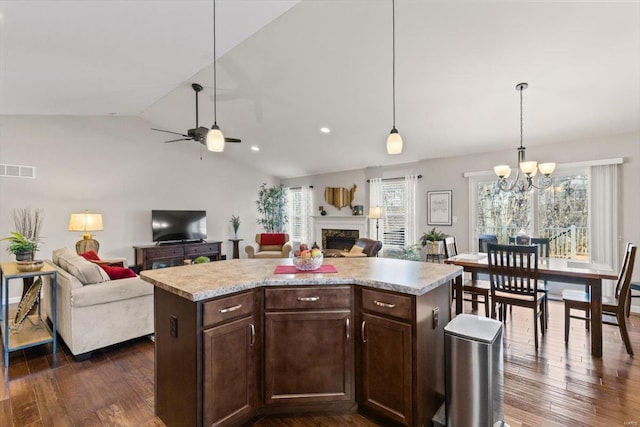 kitchen with dark hardwood / wood-style flooring, decorative light fixtures, vaulted ceiling, and a kitchen island