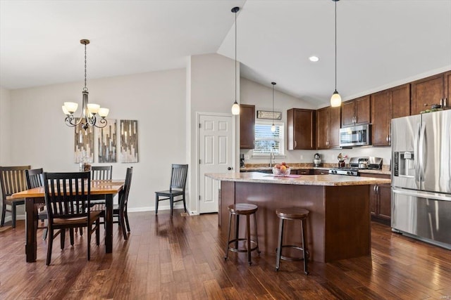 kitchen with dark hardwood / wood-style floors, lofted ceiling, hanging light fixtures, a center island, and stainless steel appliances