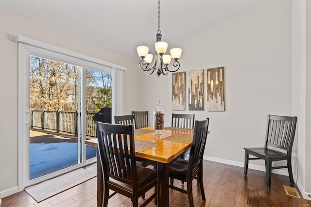 dining space featuring dark hardwood / wood-style flooring, vaulted ceiling, and a notable chandelier