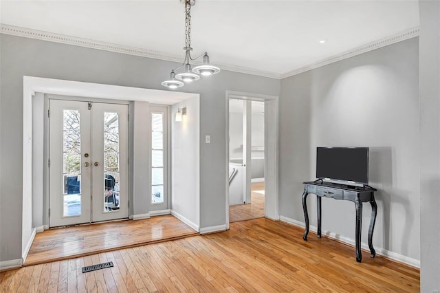 foyer featuring ornamental molding, light hardwood / wood-style floors, and french doors