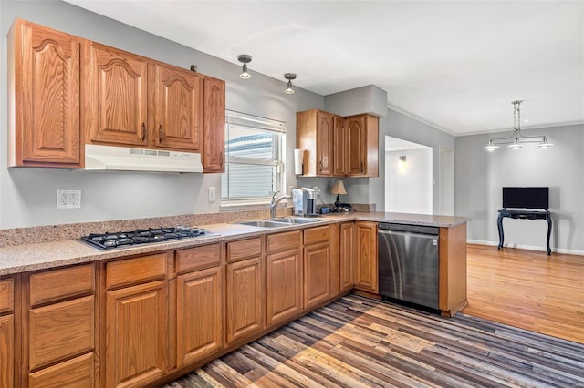 kitchen featuring sink, appliances with stainless steel finishes, hanging light fixtures, kitchen peninsula, and light wood-type flooring