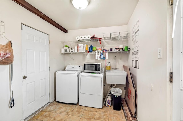 laundry room with light tile patterned floors, washer and clothes dryer, and sink