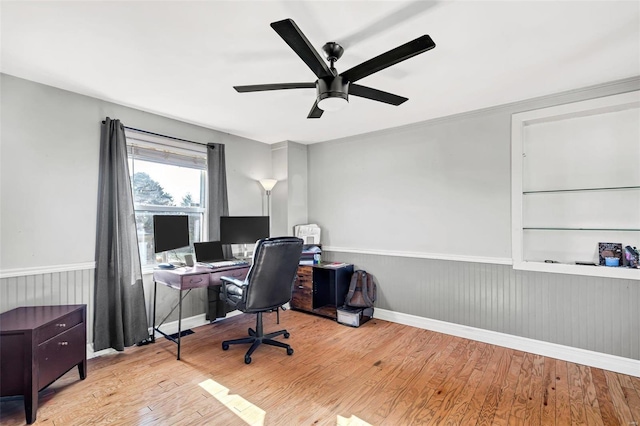 office space with built in shelves, ceiling fan, and light wood-type flooring