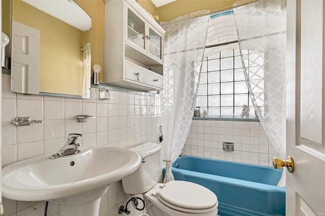 full bathroom featuring toilet, sink, tile walls, shower / bath combo with shower curtain, and decorative backsplash