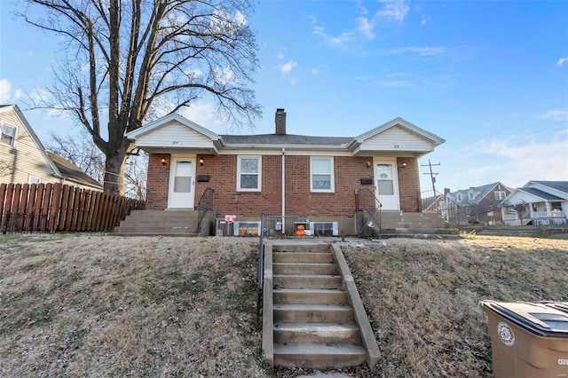 single story home featuring brick siding, a chimney, and fence