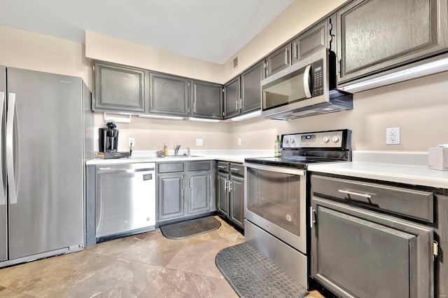 kitchen with light tile patterned flooring, appliances with stainless steel finishes, sink, and gray cabinetry