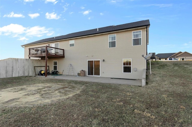 rear view of house featuring a wooden deck, a patio, and a lawn