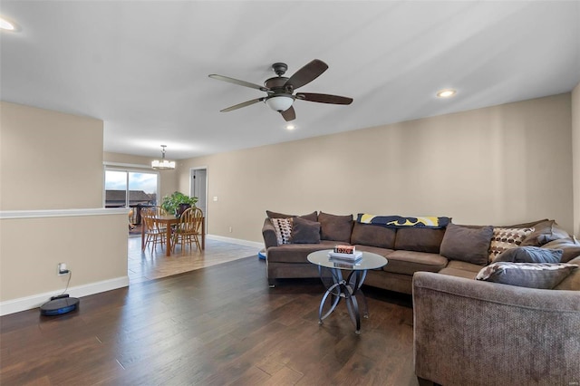 living room with ceiling fan with notable chandelier and dark hardwood / wood-style floors