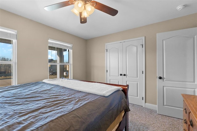 carpeted bedroom with multiple windows, ceiling fan, and a closet