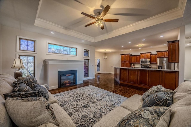 living room featuring crown molding, a tray ceiling, and dark hardwood / wood-style floors