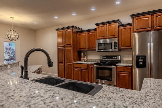 kitchen with sink, an inviting chandelier, hanging light fixtures, appliances with stainless steel finishes, and light stone countertops