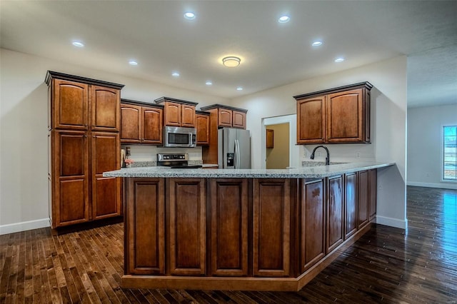 kitchen with appliances with stainless steel finishes, dark wood-type flooring, sink, and kitchen peninsula