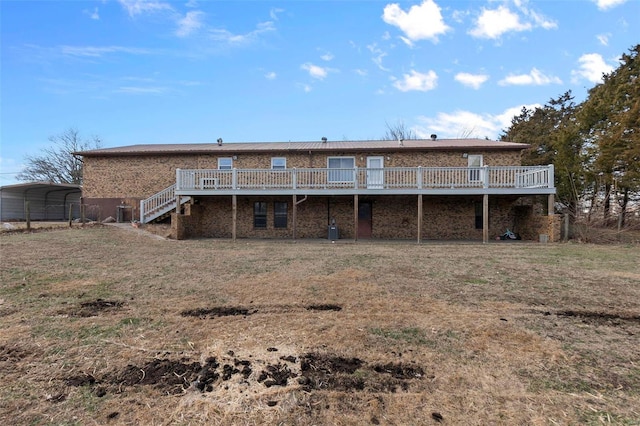 rear view of property with a wooden deck, a carport, and a yard