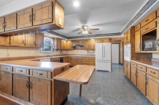 kitchen featuring ceiling fan, a kitchen island, a textured ceiling, and white appliances