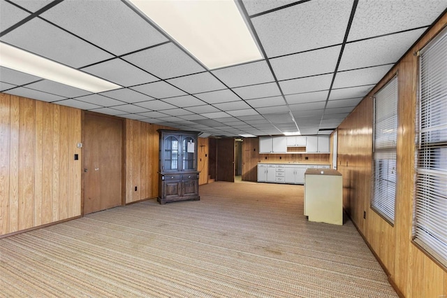 kitchen with light carpet, wood walls, and kitchen peninsula