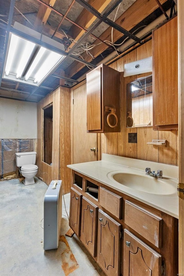 bathroom featuring vanity, concrete floors, toilet, and wood walls