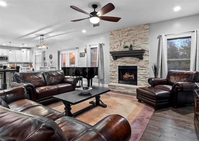 living room with hardwood / wood-style flooring, ceiling fan, and a fireplace