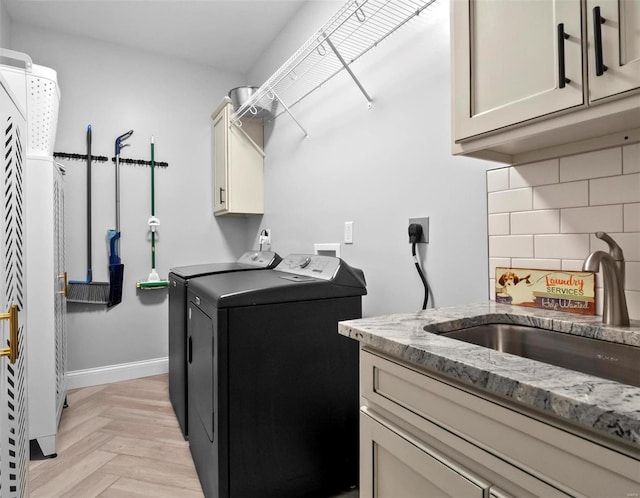 washroom featuring sink, washing machine and dryer, cabinets, and light parquet flooring