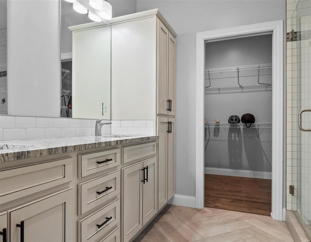 bathroom with a shower with door, vanity, and parquet floors