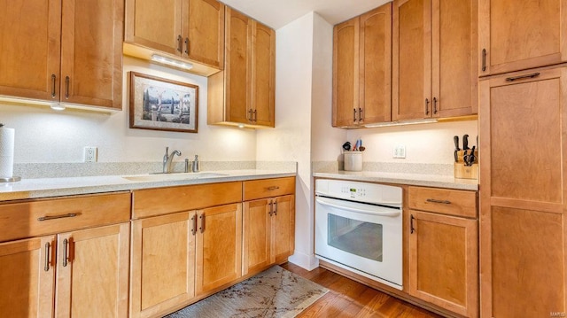 kitchen featuring oven, sink, and light wood-type flooring